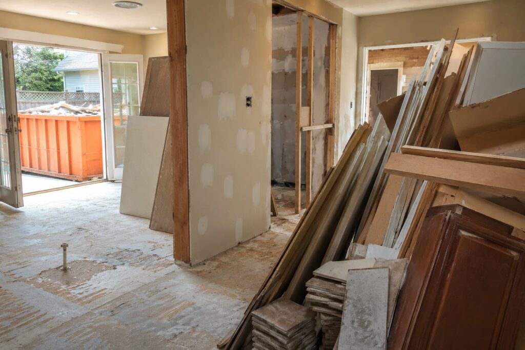 mixed home remodel debris including drywall, tile, lumber, and old cabinets staged beside a home renovation dumpster Washington IL during residential construction cleanup project