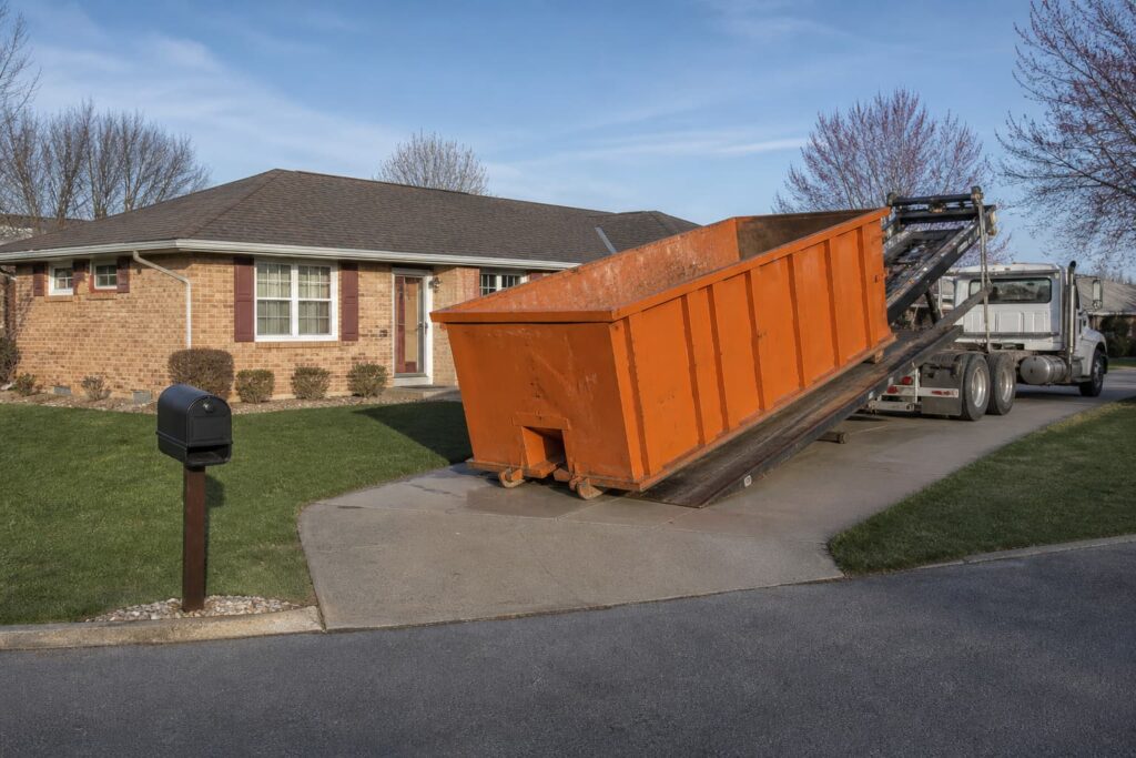dumpster rental near me Pekin IL — orange roll-off container being placed in a suburban driveway on a clear morning