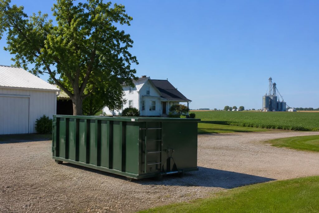Dumpster rental Hopedale IL — roll-off container on rural gravel driveway in southern Tazewell County with agricultural landscape